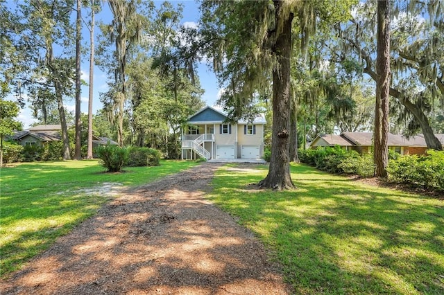 view of yard with stairway, an attached garage, and driveway