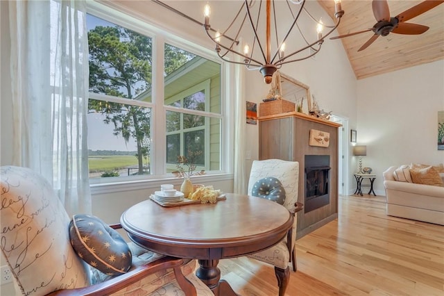 dining room featuring a ceiling fan, wood finished floors, a fireplace, and high vaulted ceiling