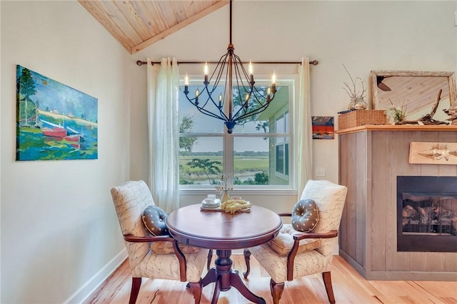 dining area featuring wood finished floors, wooden ceiling, a fireplace, baseboards, and vaulted ceiling