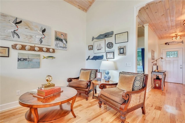 sitting room featuring light wood-style flooring, baseboards, wooden ceiling, and vaulted ceiling