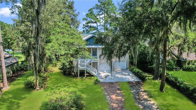 rear view of property with stairway, a lawn, driveway, and a garage