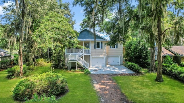 back of property with a garage, driveway, stairs, and a yard