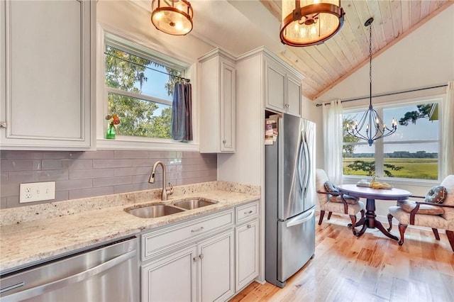 kitchen with lofted ceiling, a wealth of natural light, appliances with stainless steel finishes, and a sink