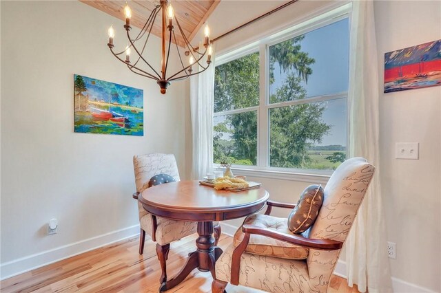 living area with a chandelier, baseboards, and wood finished floors