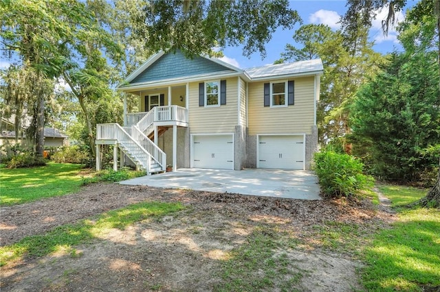 coastal inspired home featuring a front lawn, driveway, stairway, covered porch, and a garage