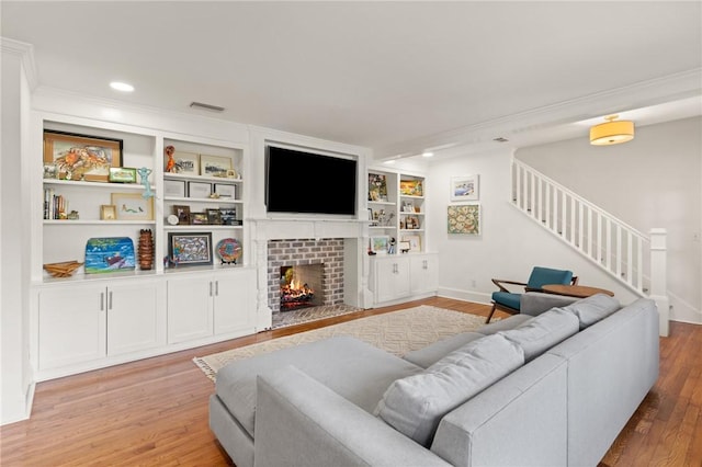 living room featuring ornamental molding, light hardwood / wood-style flooring, and built in shelves