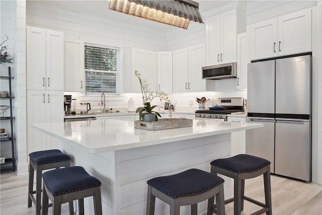 kitchen featuring white cabinetry, a breakfast bar area, a center island, stainless steel appliances, and light wood-type flooring