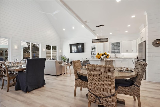 dining area featuring high vaulted ceiling, sink, and light hardwood / wood-style floors