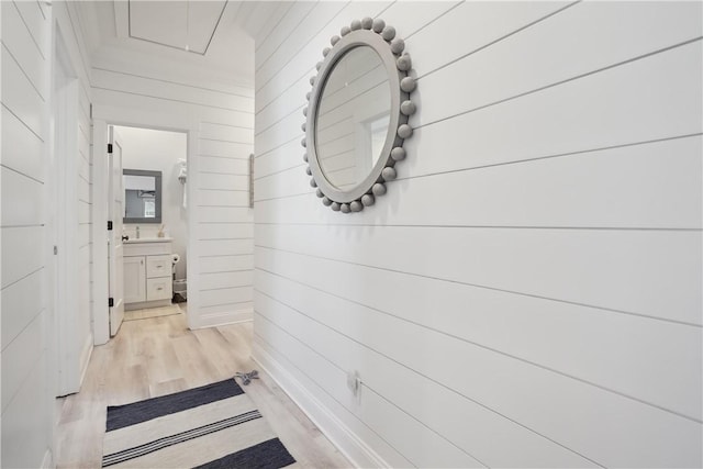 hall featuring sink, light hardwood / wood-style floors, and wood walls