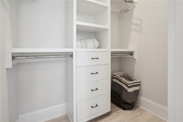 walk in closet with light hardwood / wood-style floors