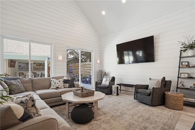 living room with high vaulted ceiling, plenty of natural light, and hardwood / wood-style floors