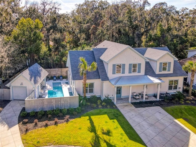 view of front of house featuring a fenced in pool, an outbuilding, a patio area, and a front lawn