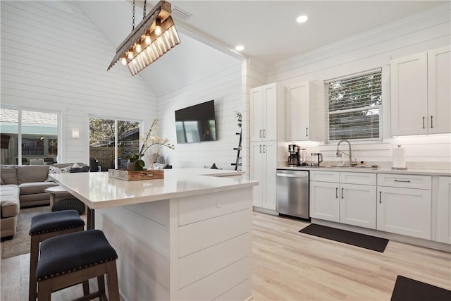 kitchen with white cabinetry, pendant lighting, stainless steel dishwasher, and a kitchen bar