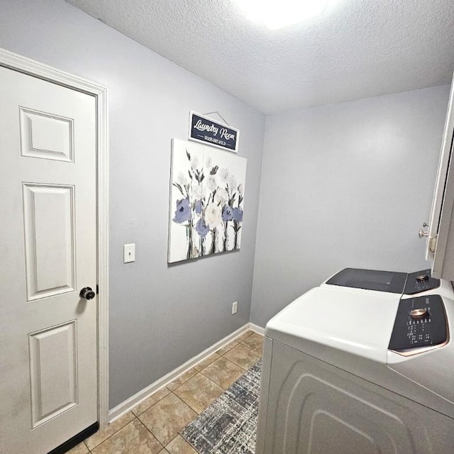 laundry room with light tile patterned flooring, cabinets, washer and clothes dryer, and a textured ceiling