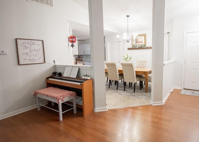 miscellaneous room with lofted ceiling, hardwood / wood-style floors, and a chandelier