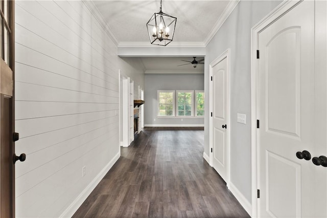 corridor with a notable chandelier, dark hardwood / wood-style flooring, ornamental molding, and a textured ceiling