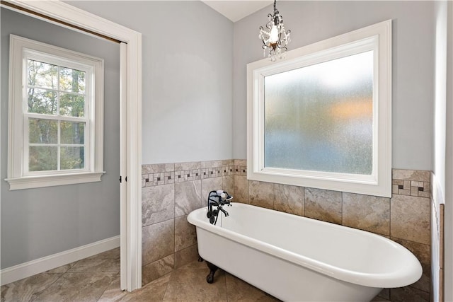 bathroom featuring a bathing tub, tile walls, and a notable chandelier