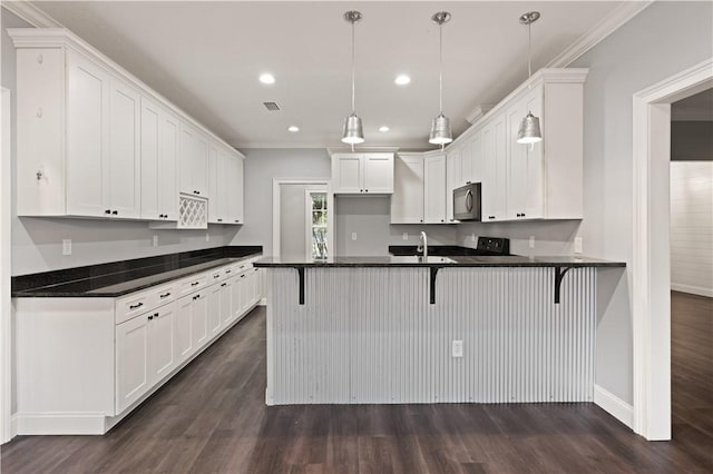 kitchen featuring pendant lighting, a kitchen breakfast bar, crown molding, dark hardwood / wood-style flooring, and white cabinetry