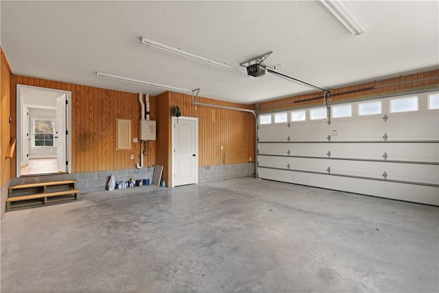 garage featuring wooden walls, a garage door opener, and water heater