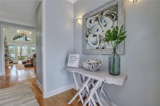 interior space featuring wood-type flooring, crown molding, and a chandelier