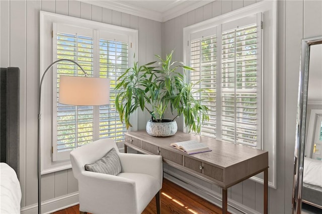 living area featuring crown molding, wood finished floors, and a decorative wall