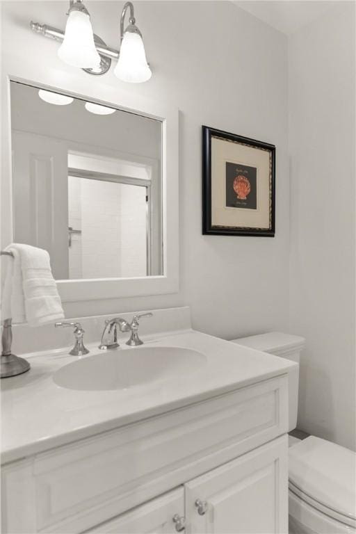 bathroom with toilet, a shower with door, and vanity