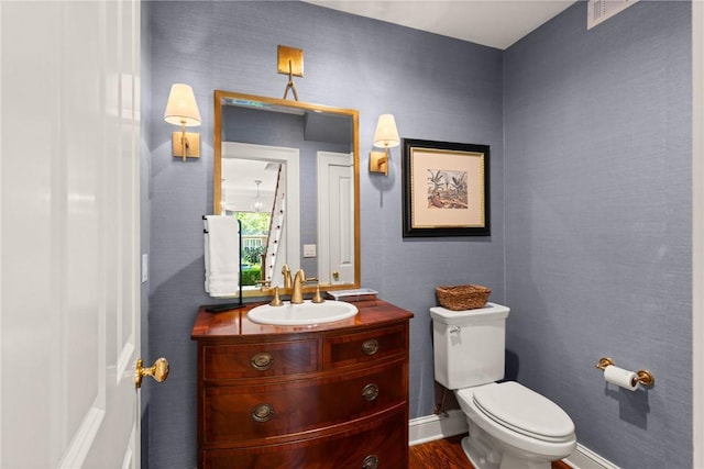 half bathroom featuring toilet, visible vents, and vanity