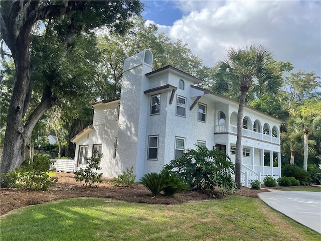 view of front of house with a balcony and a front yard