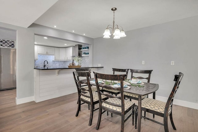 dining room featuring light wood-type flooring, an inviting chandelier, and sink