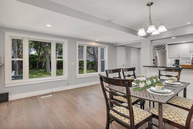 dining space featuring a notable chandelier and light wood-type flooring