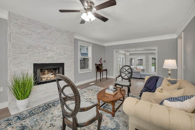 living room featuring a fireplace, hardwood / wood-style flooring, ceiling fan, and crown molding