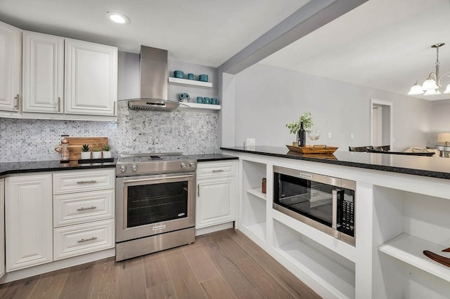 kitchen with wall chimney exhaust hood, stainless steel appliances, dark wood-type flooring, a chandelier, and white cabinetry