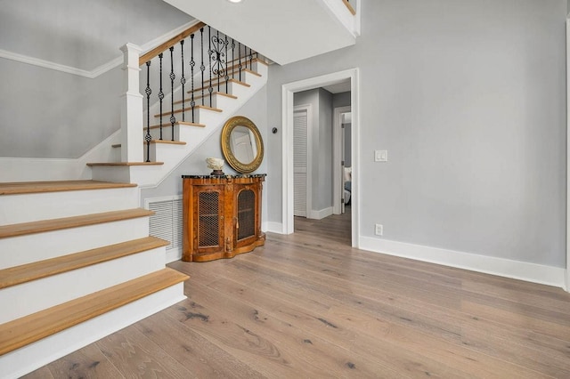 staircase featuring hardwood / wood-style floors and ornamental molding