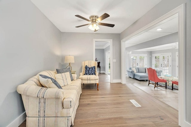 living room with ceiling fan and light hardwood / wood-style flooring