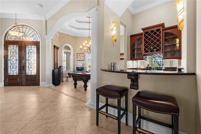 bar with ornamental molding, light tile patterned flooring, decorative light fixtures, french doors, and ornate columns