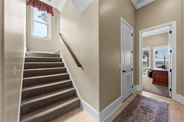 stairway featuring tile patterned flooring, crown molding, and a wealth of natural light