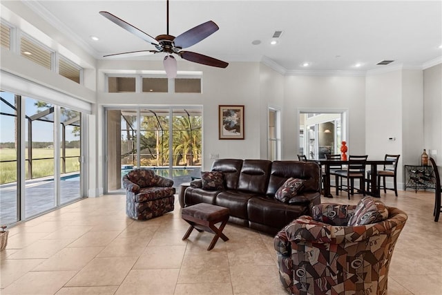 living room featuring light tile patterned floors, crown molding, ceiling fan, and a towering ceiling