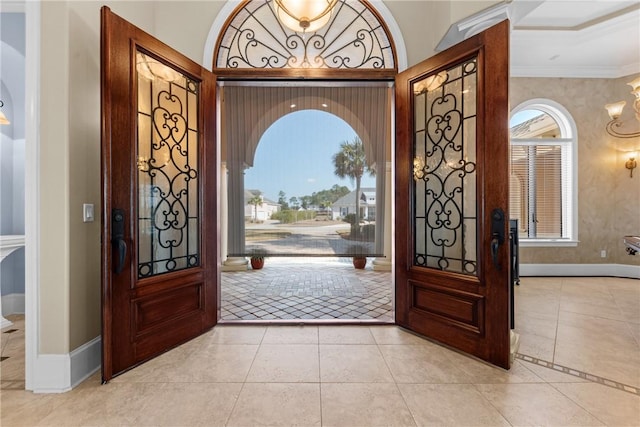 foyer with light tile patterned floors, crown molding, and a healthy amount of sunlight