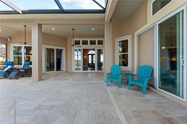 view of patio with ceiling fan and glass enclosure