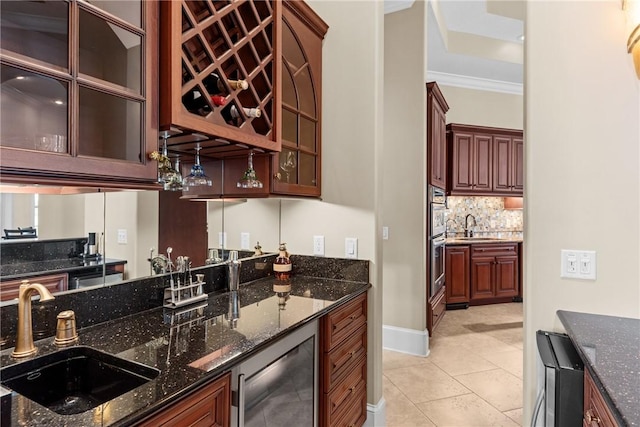 kitchen with dark stone countertops, sink, backsplash, and beverage cooler