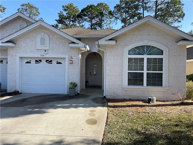 ranch-style house with stucco siding, an attached garage, concrete driveway, and a shingled roof