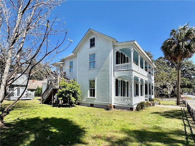 rear view of house featuring a balcony, covered porch, stairs, and a yard