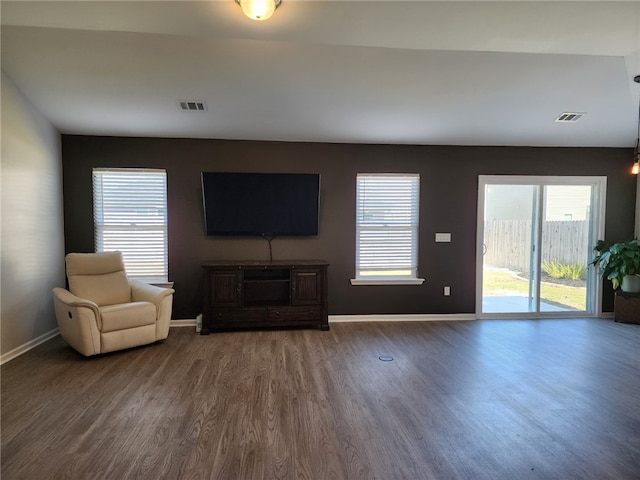 unfurnished living room featuring visible vents, baseboards, and wood finished floors