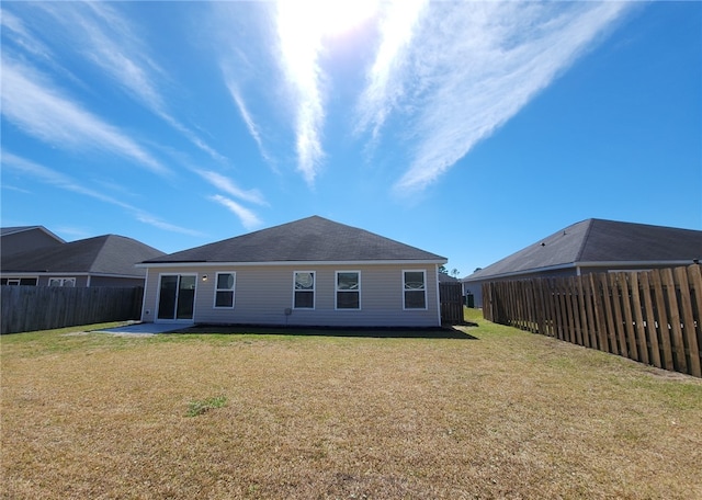 rear view of house with a yard, a fenced backyard, and a patio area