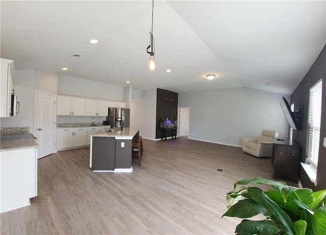 kitchen with light wood-type flooring, an island with sink, open floor plan, stainless steel appliances, and lofted ceiling