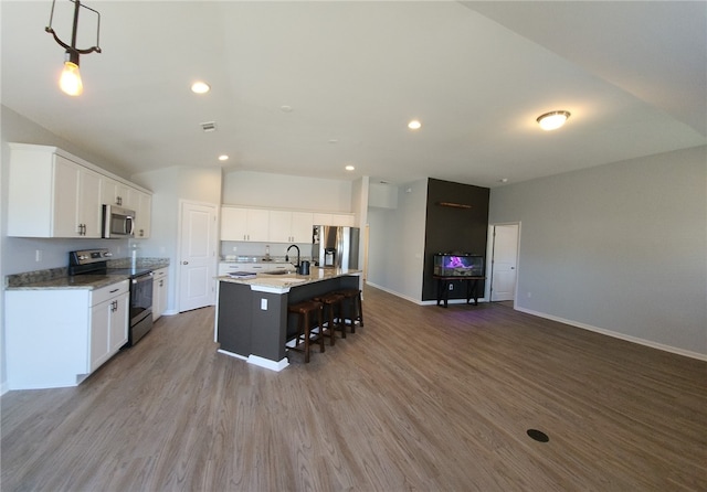 kitchen featuring a sink, a kitchen bar, appliances with stainless steel finishes, and wood finished floors