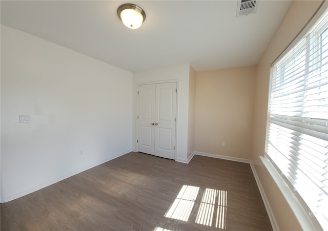 spare room with visible vents, baseboards, and wood finished floors