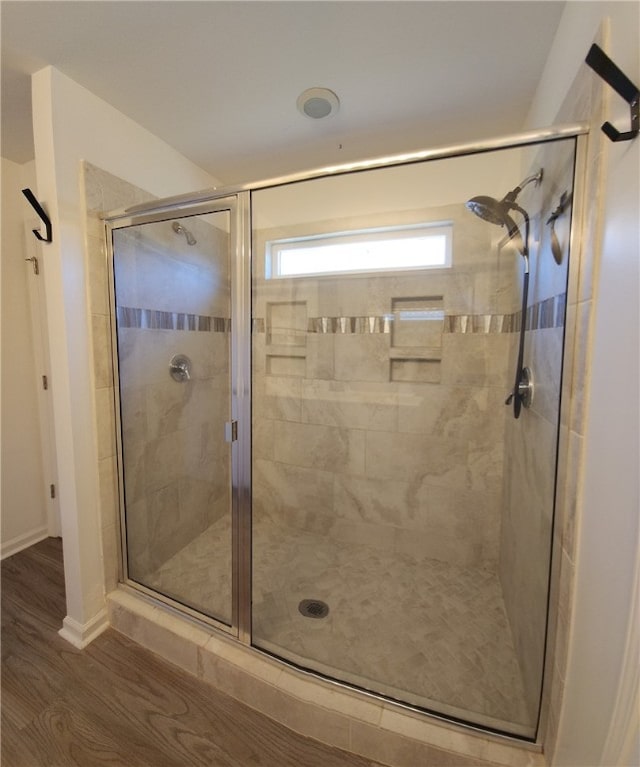 bathroom with a shower stall and wood finished floors