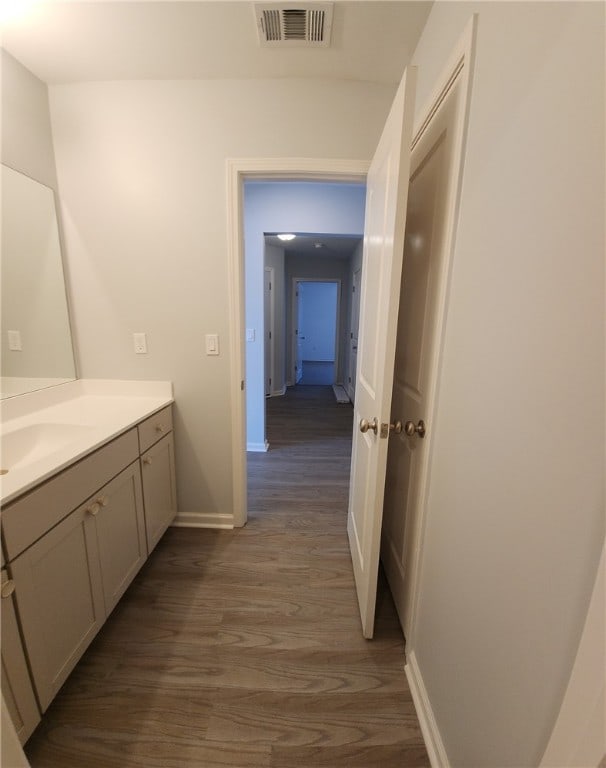 bathroom featuring visible vents, baseboards, wood finished floors, and vanity