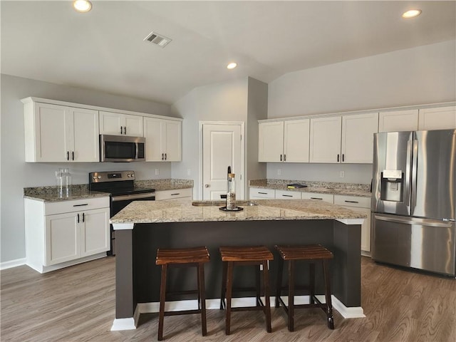 kitchen with visible vents, lofted ceiling, a sink, appliances with stainless steel finishes, and white cabinetry